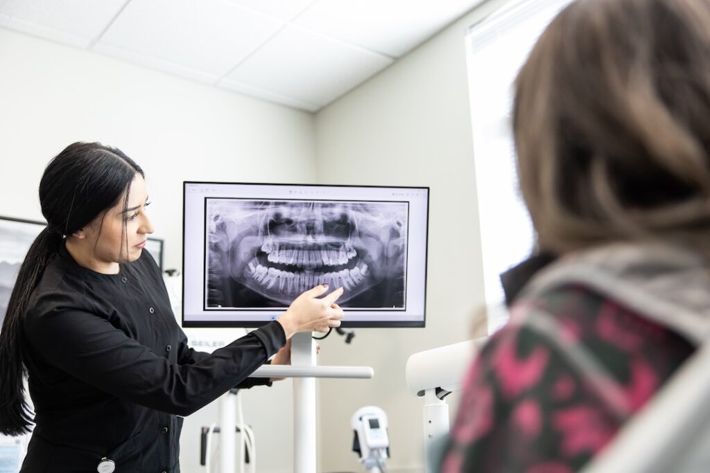 Dental professional explaining an X-ray image of teeth to a patient in a modern dental office, highlighting the importance of dental health and treatment options.