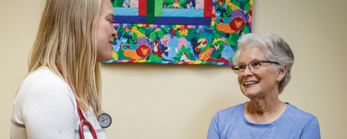 A healthcare professional engaging in a friendly conversation with an elderly patient in a warmly decorated clinic, promoting a supportive and caring environment.